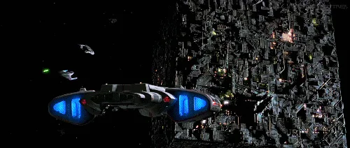 A spaceship flies past a massive space station, firing red and green lasers at it. The ship then dodges a large explosion…