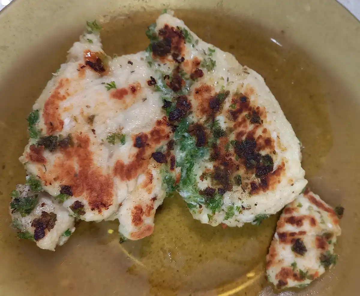 A close-up photo shows a piece of cooked, white meat on a brown plate, with visible herbs and browned spots. The overlaid…