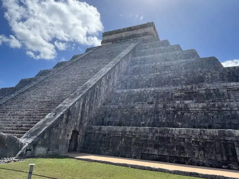 the image shows the pyramid of kukulkan at chichen itza, mexico, a massive stone structure with steep steps and a temple on…
