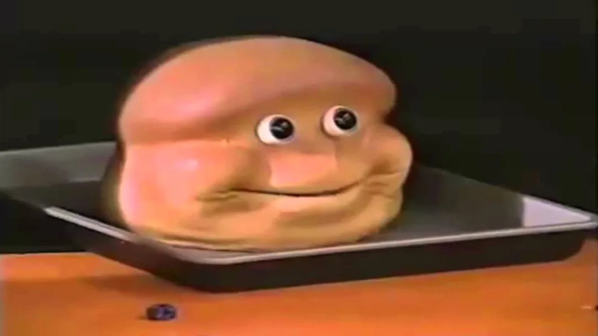 A close-up of a cartoonish, anthropomorphic slice of bread with large, bulging eyes and a wide, slightly smug smile, sitting…