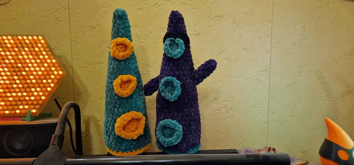 Two crocheted plush toys resembling characters from the game 'Undertale' stand side by side on a shelf. The one on the left…