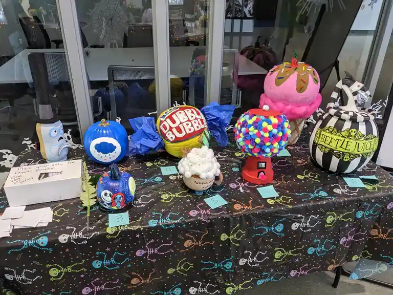 A table displays seven creatively decorated pumpkins themed after pop culture and candy, including a 'Dubble Bubble' gumball…