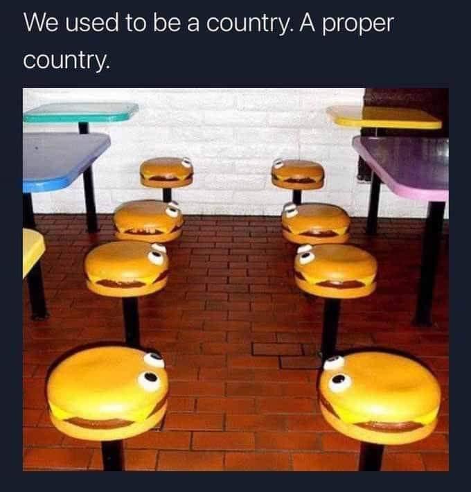 The image shows a restaurant interior with several burger-shaped stools, each with googly eyes painted on them, arranged on…