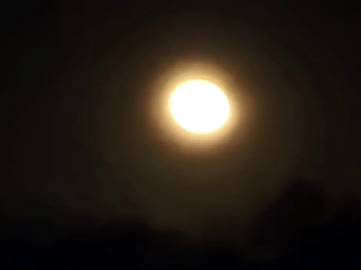 A bright, glowing orb, likely the sun or moon, is centered in a dark sky with faint clouds at the bottom. Overlaid text…