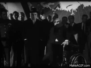 A black-and-white sequence from a 1940s film shows a man in a wheelchair being pushed by a group of men, then standing up…