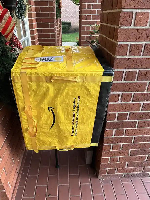 A large, yellow Amazon Logistics shipping bag, marked 'Property of Amazon Logistics Not for resale/unauthorized use', is…