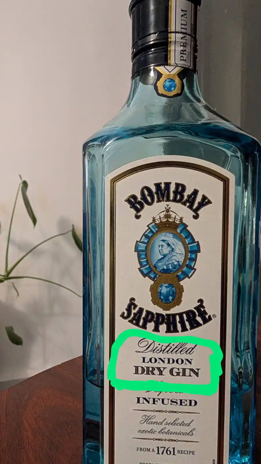 A close-up photo of a blue Bombay Sapphire gin bottle, with a bright green hand-drawn circle highlighting the text…