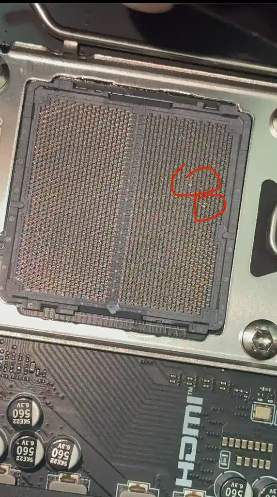 a close-up photograph of a computer motherboard's cpu socket, showing a grid of metallic pins. A red hand-drawn circle…