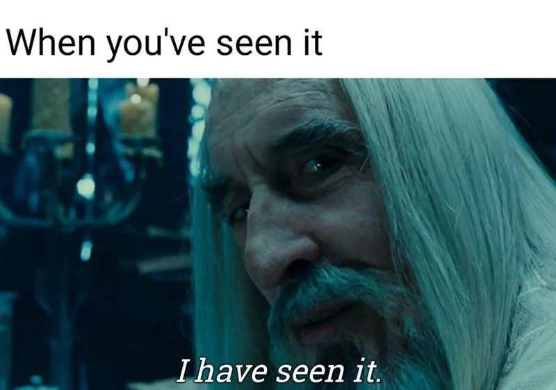 A close-up shot of a man with long white hair and a beard, looking intently at the viewer with a knowing, slightly sinister…