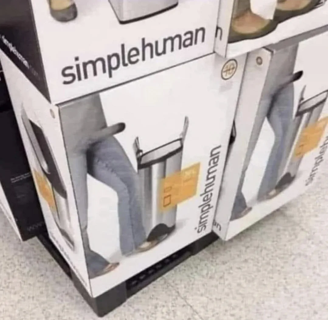 A photo of stacked 'simplehuman' trash can boxes in a store, where the product images on the boxes show a person's legs and…