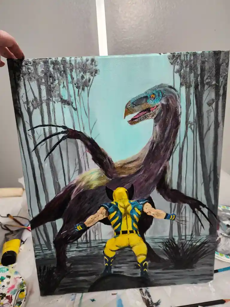 A hand holds up a painted canvas depicting Wolverine in his yellow and blue suit, facing a large, feathered raptor in a…