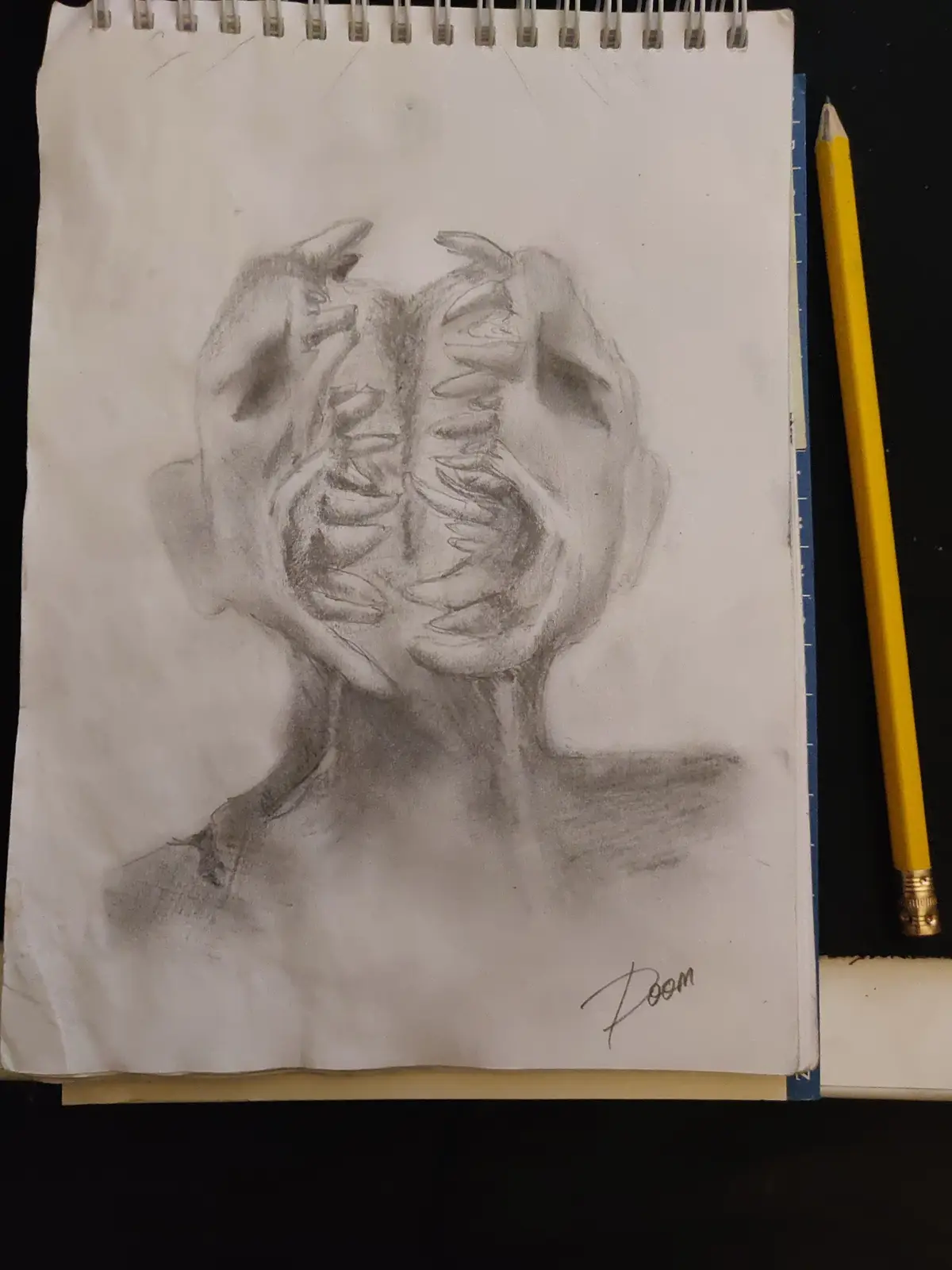 A pencil sketch on a spiral-bound notebook page depicts a grotesque, screaming face with its mouth torn open to reveal ribs…