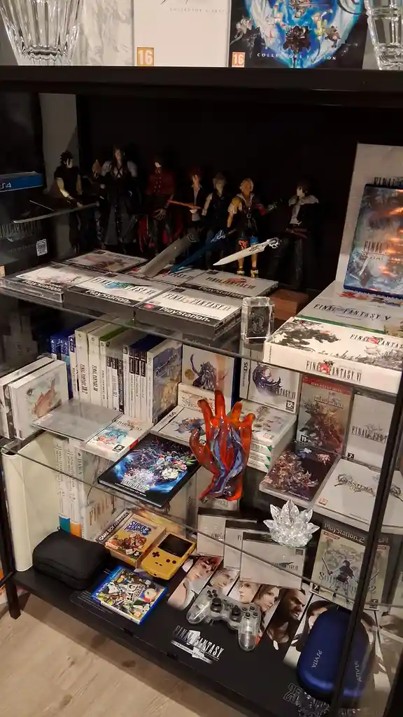 A glass display case filled with numerous Final Fantasy video games across multiple platforms, including PlayStation…