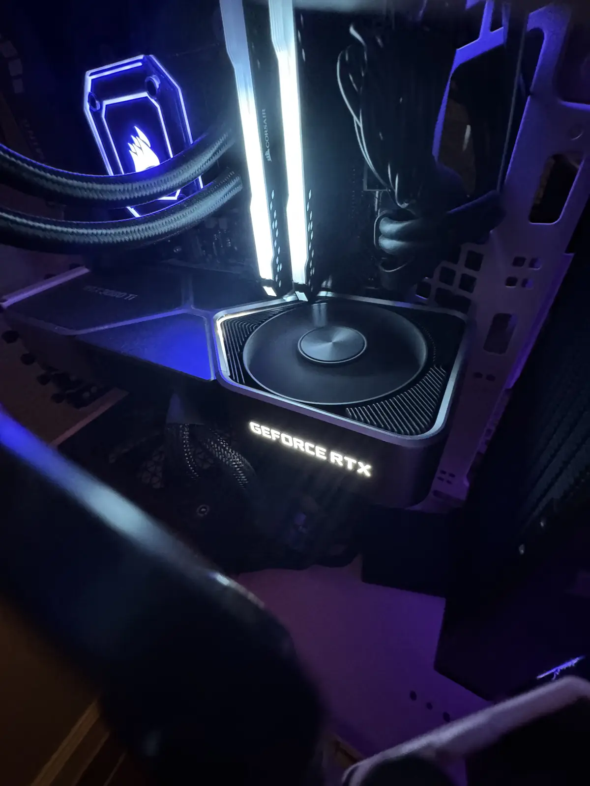 A close-up shot inside a computer case showing a GeForce RTX graphics card with glowing white lettering, next to a…