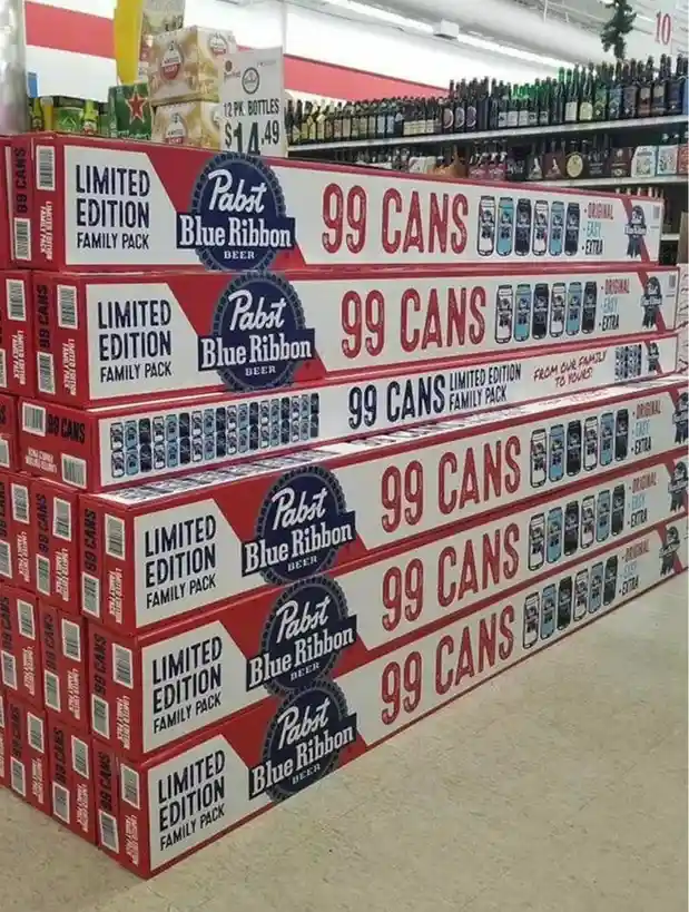 A large stack of Pabst Blue Ribbon beer boxes, each labeled 'LIMITED EDITION FAMILY PACK' and '99 CANS', is displayed in a…