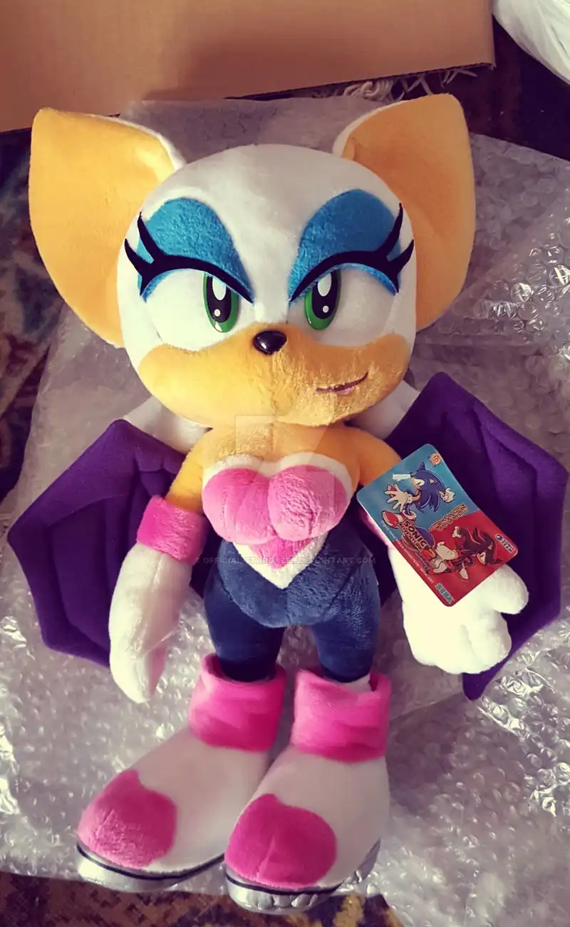 A plush toy of the character Rouge the Bat from Sonic the Hedgehog, featuring her signature white face, blue eye makeup…