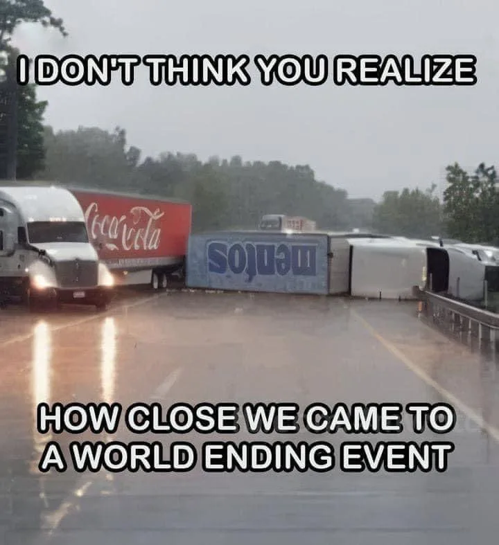 A rainy highway scene shows a Coca-Cola semi-truck stopped near a severely damaged, overturned truck with 'Medios' written…