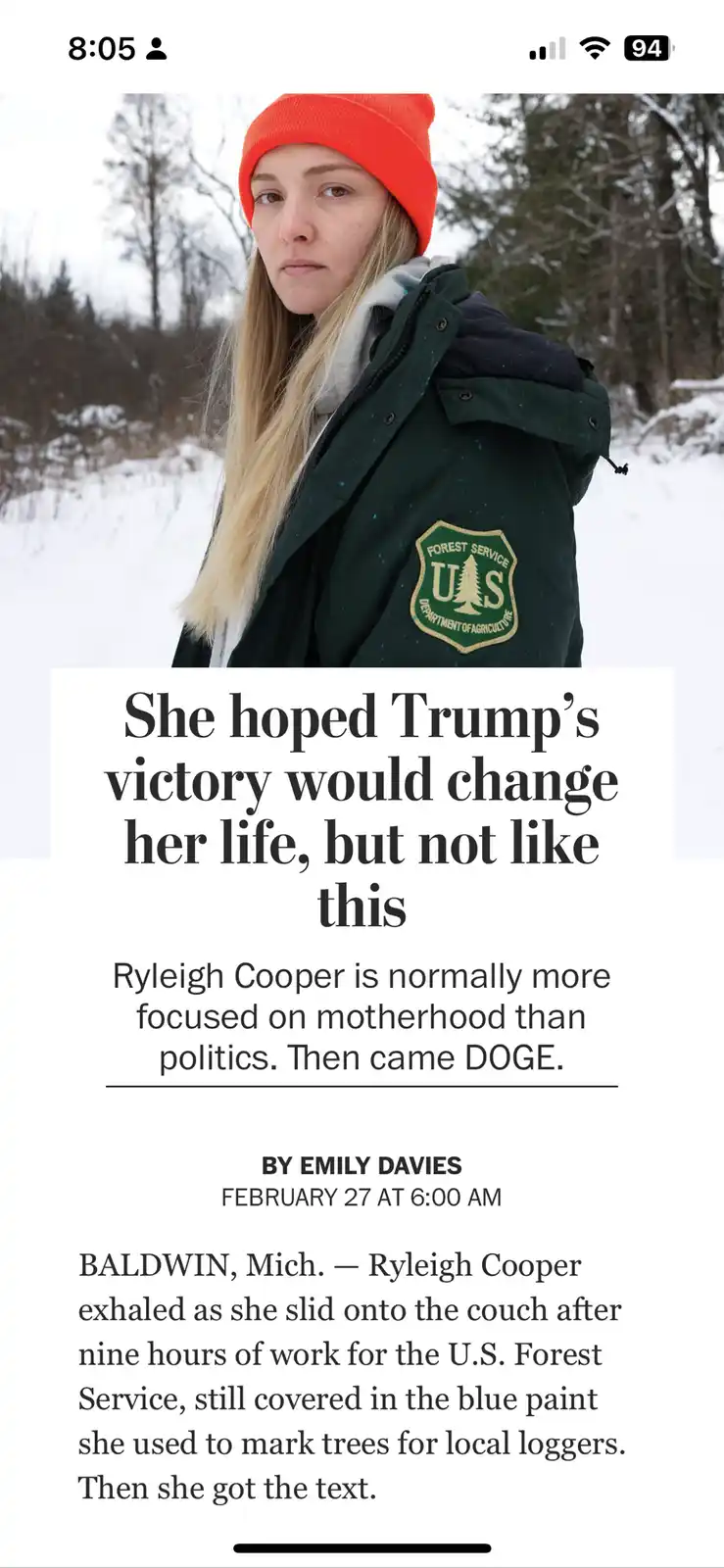 A woman with blonde hair and an orange beanie wears a green U.S. Forest Service jacket in a snowy forest. Overlaid text…