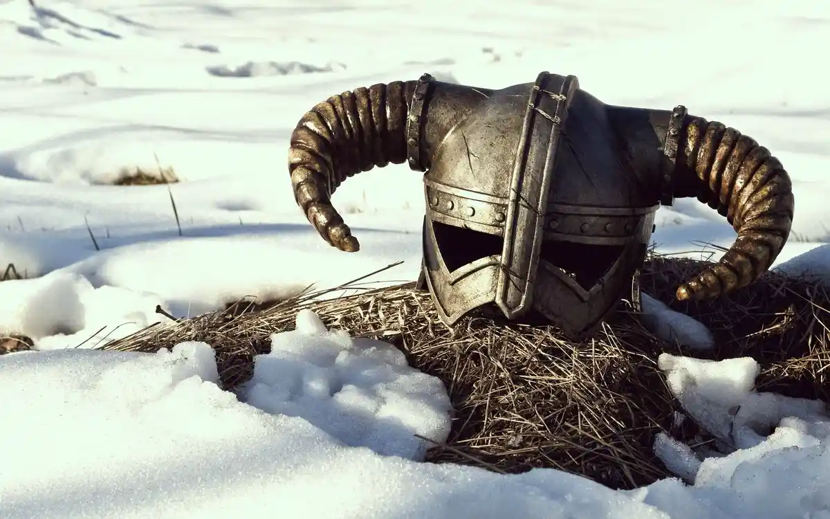 A weathered, horned fantasy helmet rests on a bed of straw partially buried in snow, with the overlaid text 'i'm not dead…