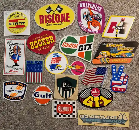 A collection of vintage American automotive and racing stickers from brands like Stant, Rislone, Wolverine, Hurst, Castrol…
