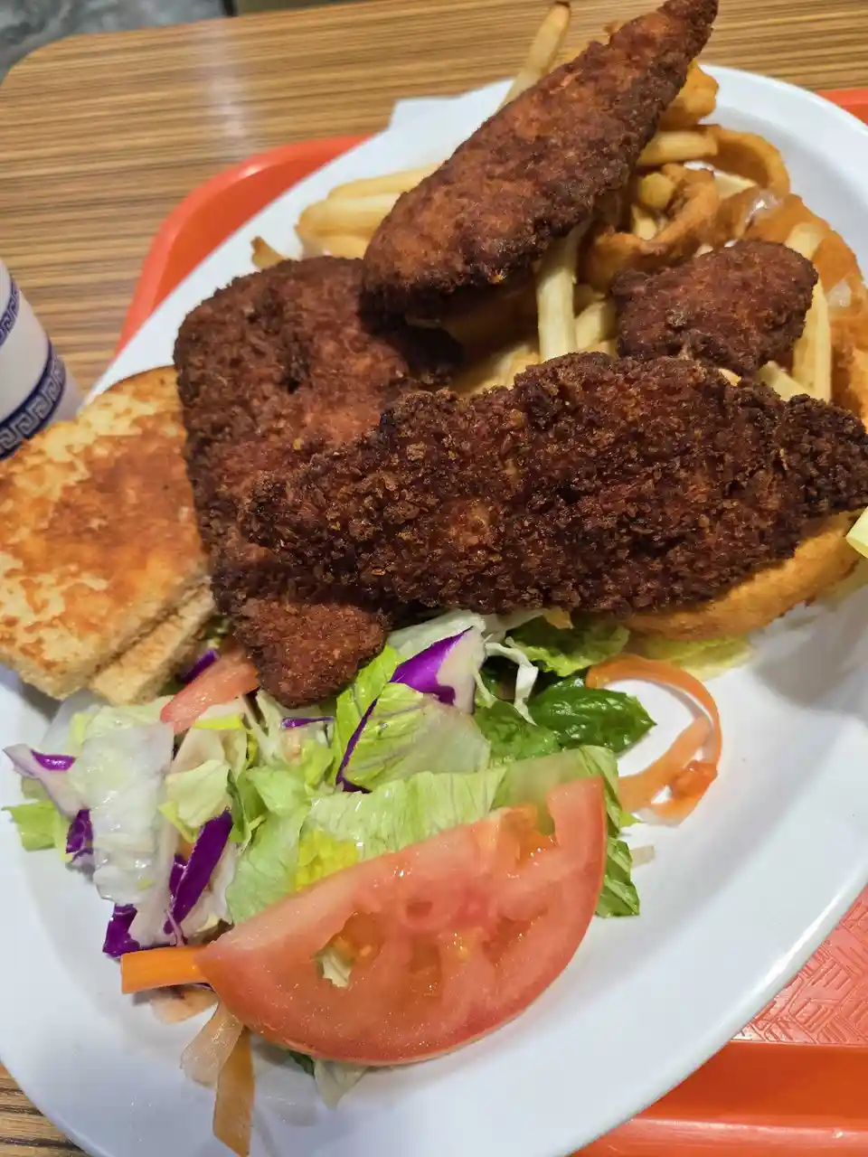 A plate of fried chicken pieces, french fries, and a side salad sits on an orange tray. The text overlay reads 'this is not…