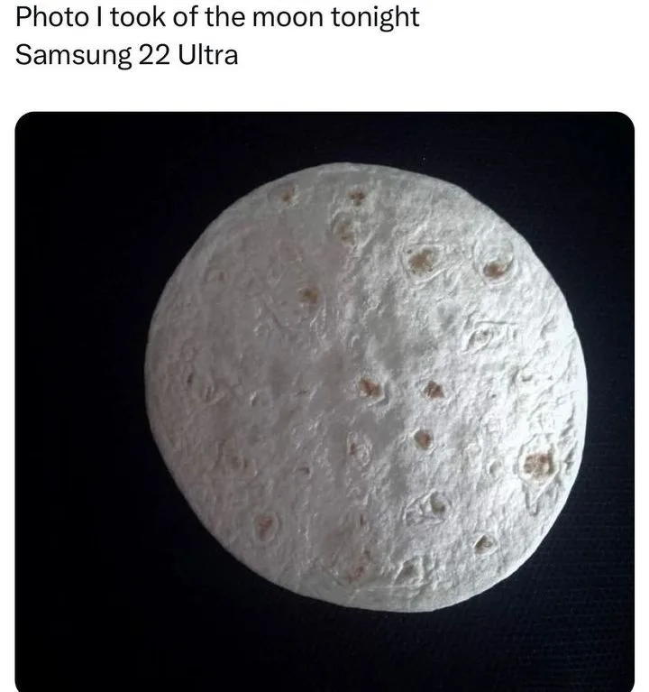 A photo shows a round, white, textured object resembling a tortilla or flatbread with brown spots, set against a dark…