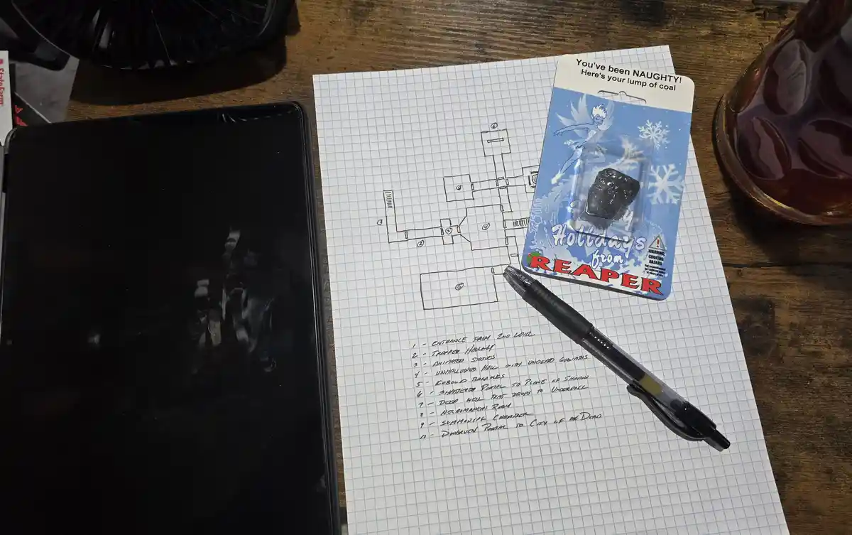 A hand-drawn dungeon map on graph paper is labeled with fantasy-themed rooms like 'Trapped Hallway' and 'Summoning Chamber'…