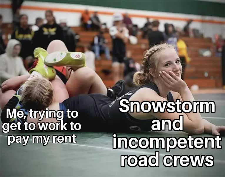 Two young women are on a gymnasium floor during what appears to be a wrestling match. One is on her back with her legs up…