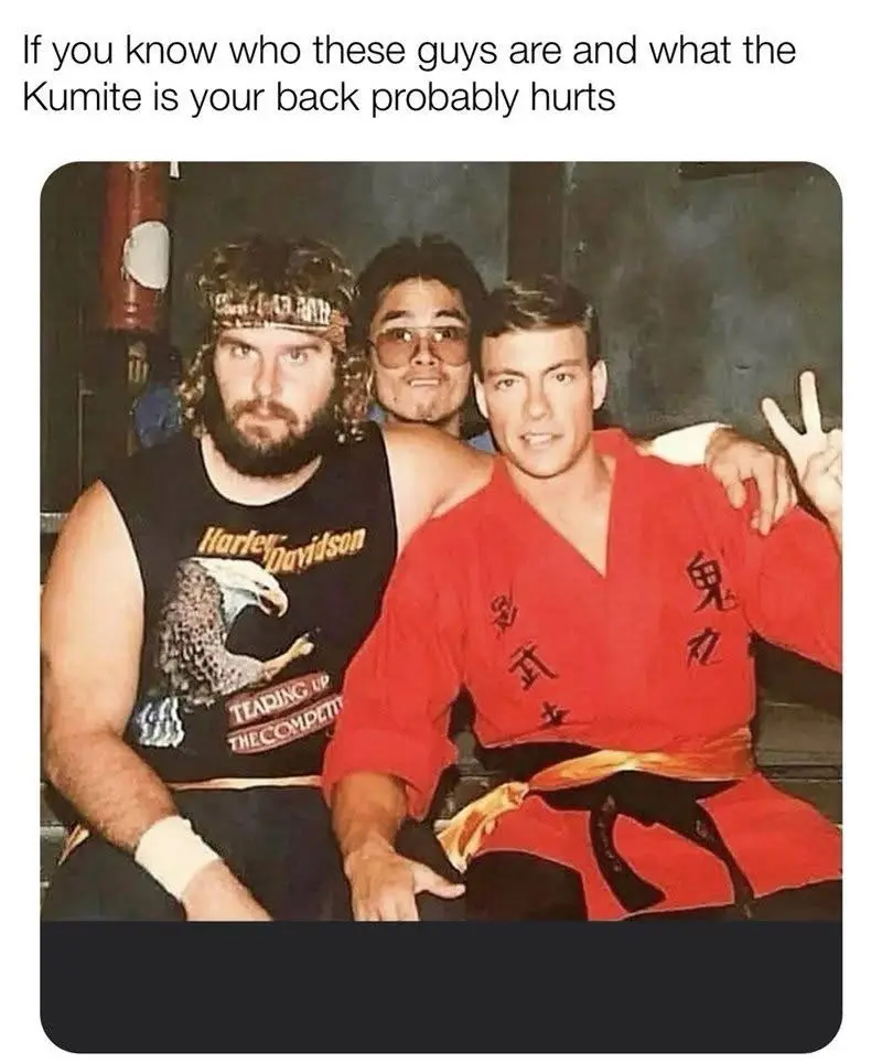 Three men are posing together in a vintage photo. The man on the left wears a Harley-Davidson tank top with an eagle graphic…