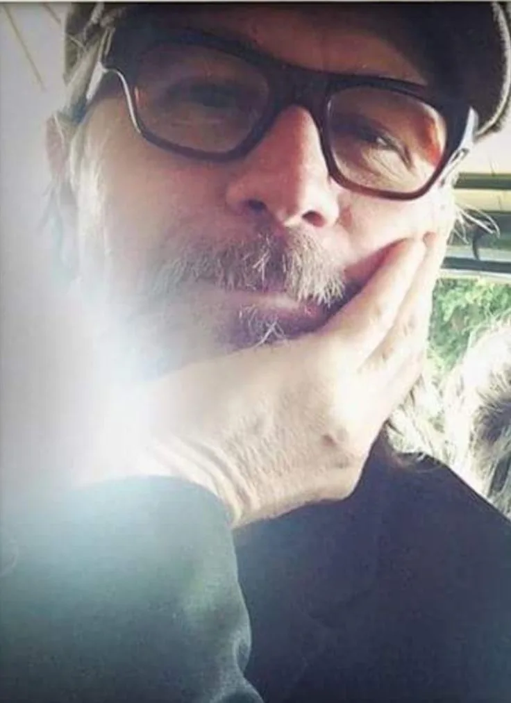 A close-up selfie of a middle-aged man with glasses and a mustache, resting his chin on his hand while looking at the…