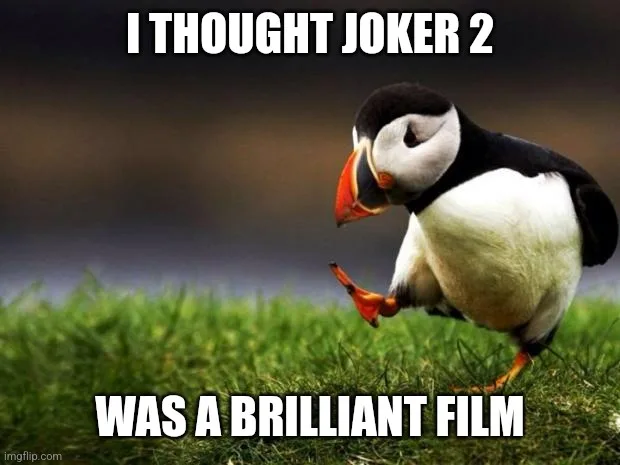 A penguin stands on grass, looking down with one foot lifted, as if in disappointment or confusion. White bold text at the…