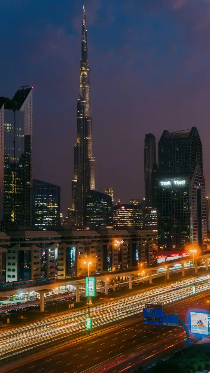 A long-exposure night photograph of Dubai's skyline, prominently featuring the Burj Khalifa towering over illuminated…