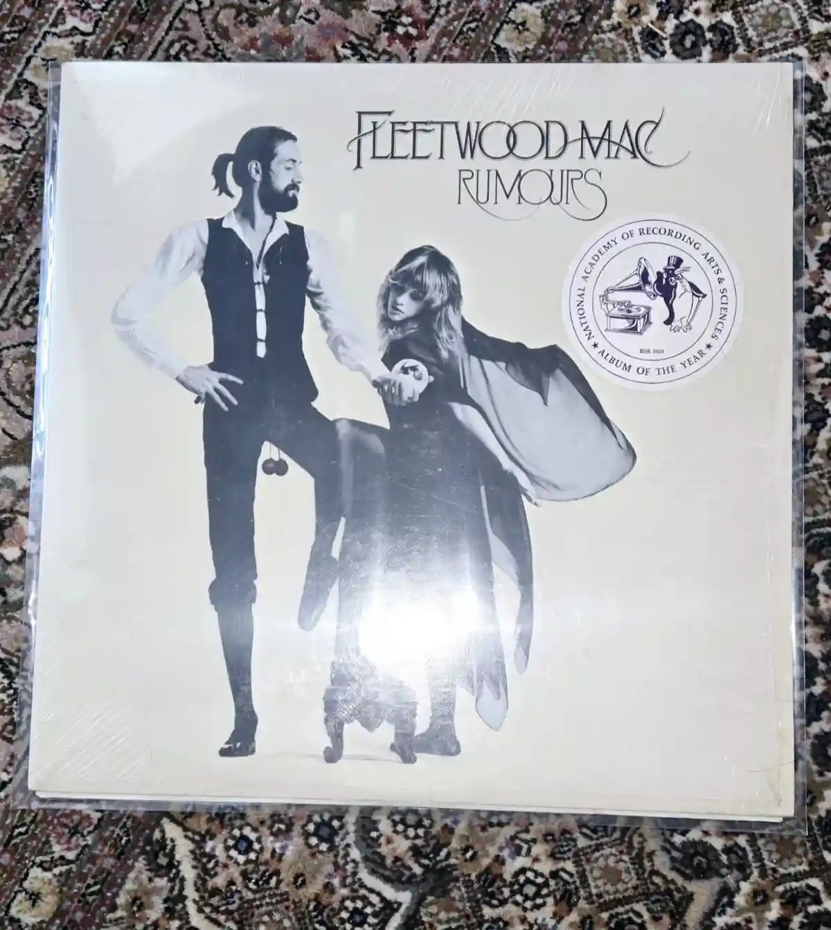 A black-and-white album cover of Fleetwood Mac's 'Rumours' is shown, featuring a man and woman in 1970s attire posing…