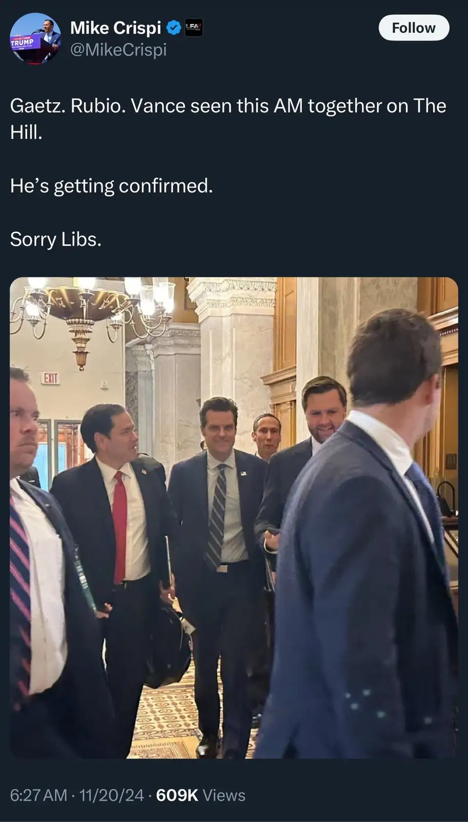 A screenshot of a tweet by Mike Crispi showing a photo of several men in suits walking through a grand hallway, likely on…