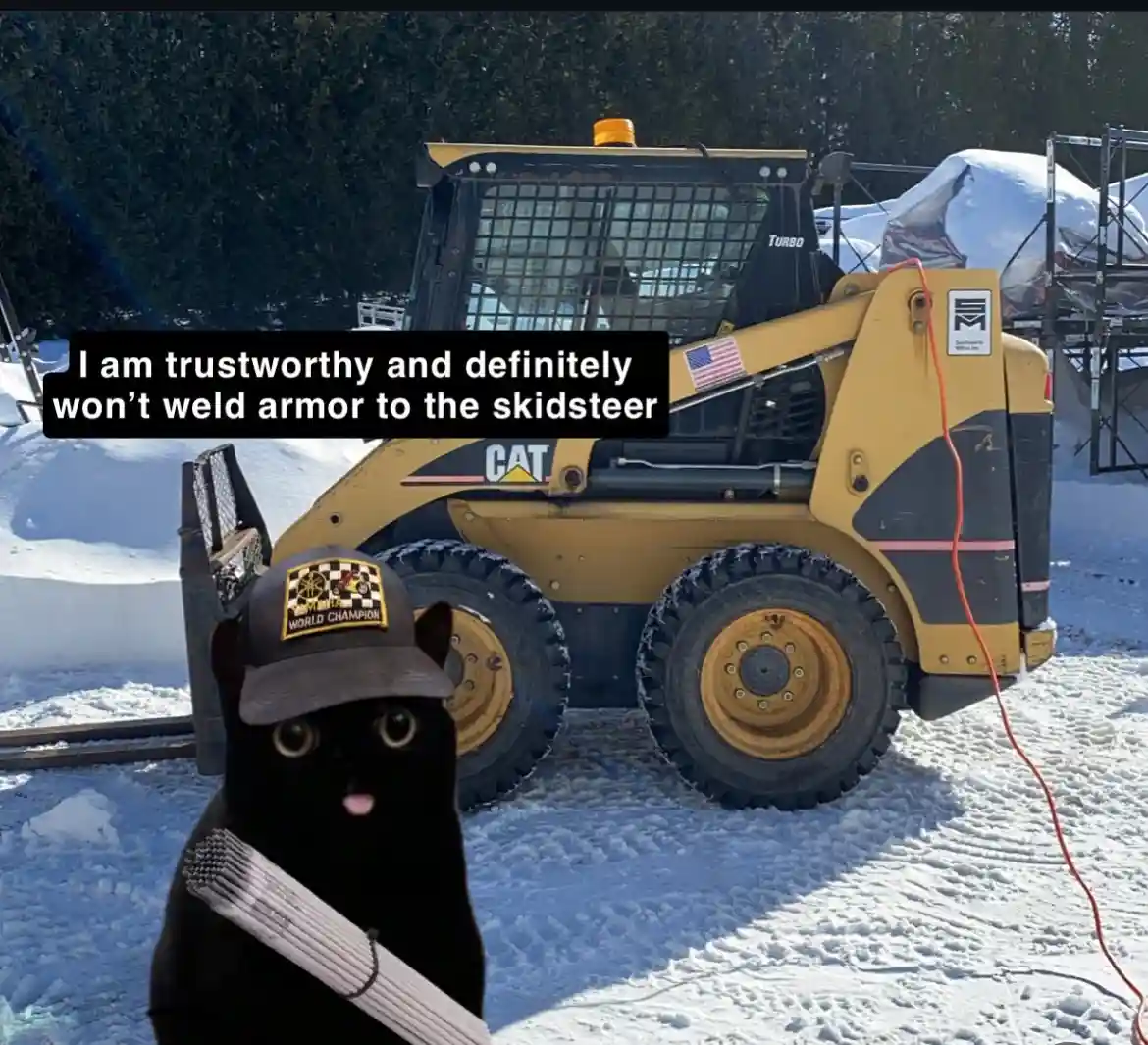 A black cat wearing a 'World Champion' cap and carrying a bundle of welding rods stands in front of a yellow CAT skid-steer…