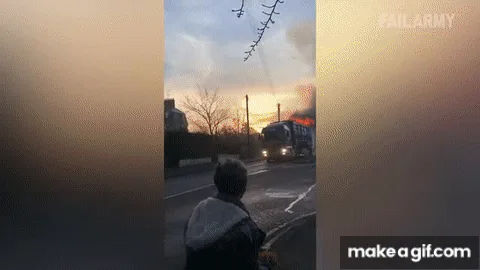 A blue semi-truck is shown on a road, initially appearing normal, then catching fire with flames and smoke billowing from…