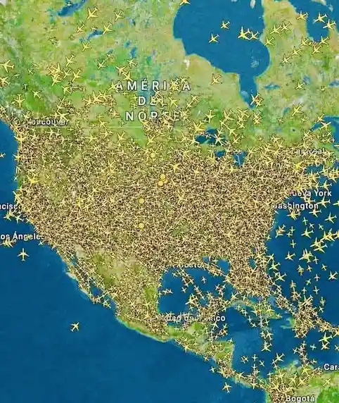 A map of North America is densely overlaid with yellow airplane icons, visually representing heavy air traffic across the…