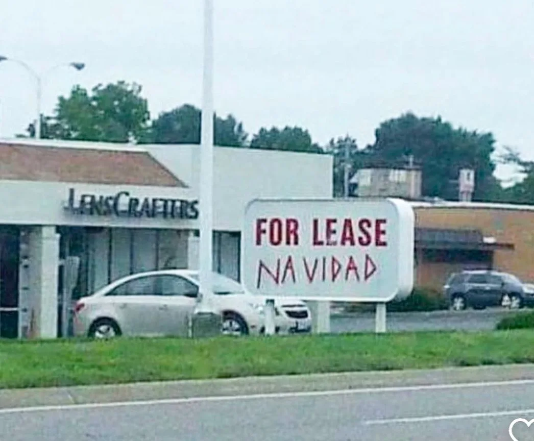 A blurry photo shows a 'FOR LEASE' sign in front of a LensCrafters store, with 'NAVIDAD' handwritten underneath in red…