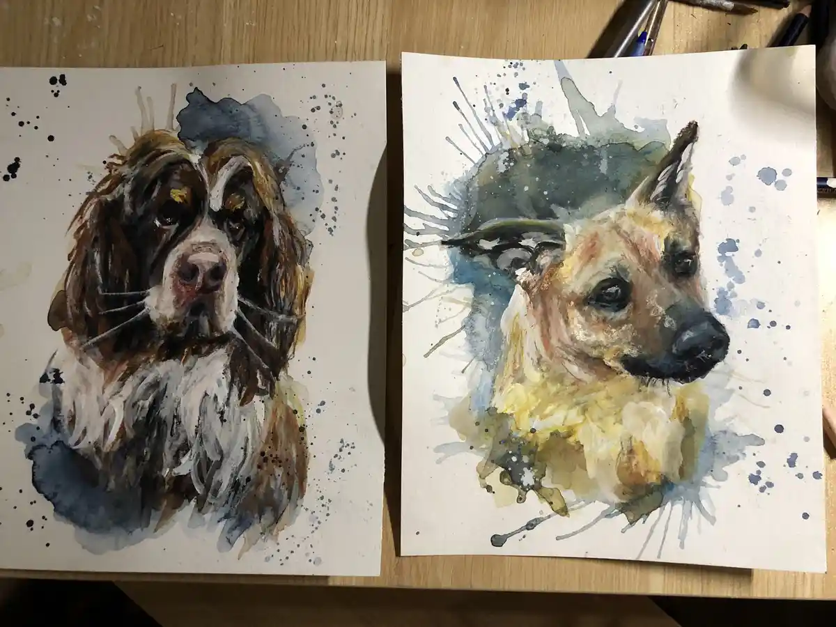 Two watercolor dog portraits side-by-side on a wooden table; the left dog, a brown and white spaniel-like breed, has text…