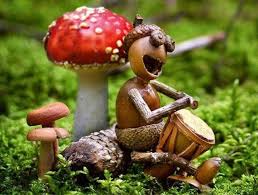 A small figurine of a squirrel wearing a hat, sitting on moss and playing a drum, next to a large red mushroom with white…
