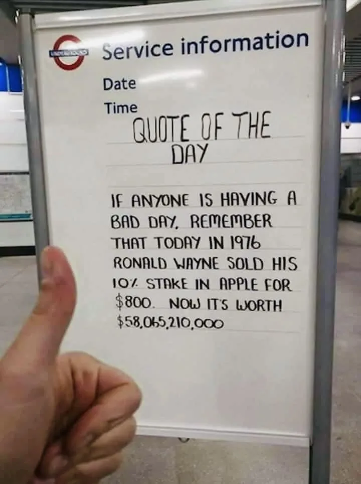 A person gives a thumbs-up next to a London Underground service information board that has been handwritten with a 'Quote of…