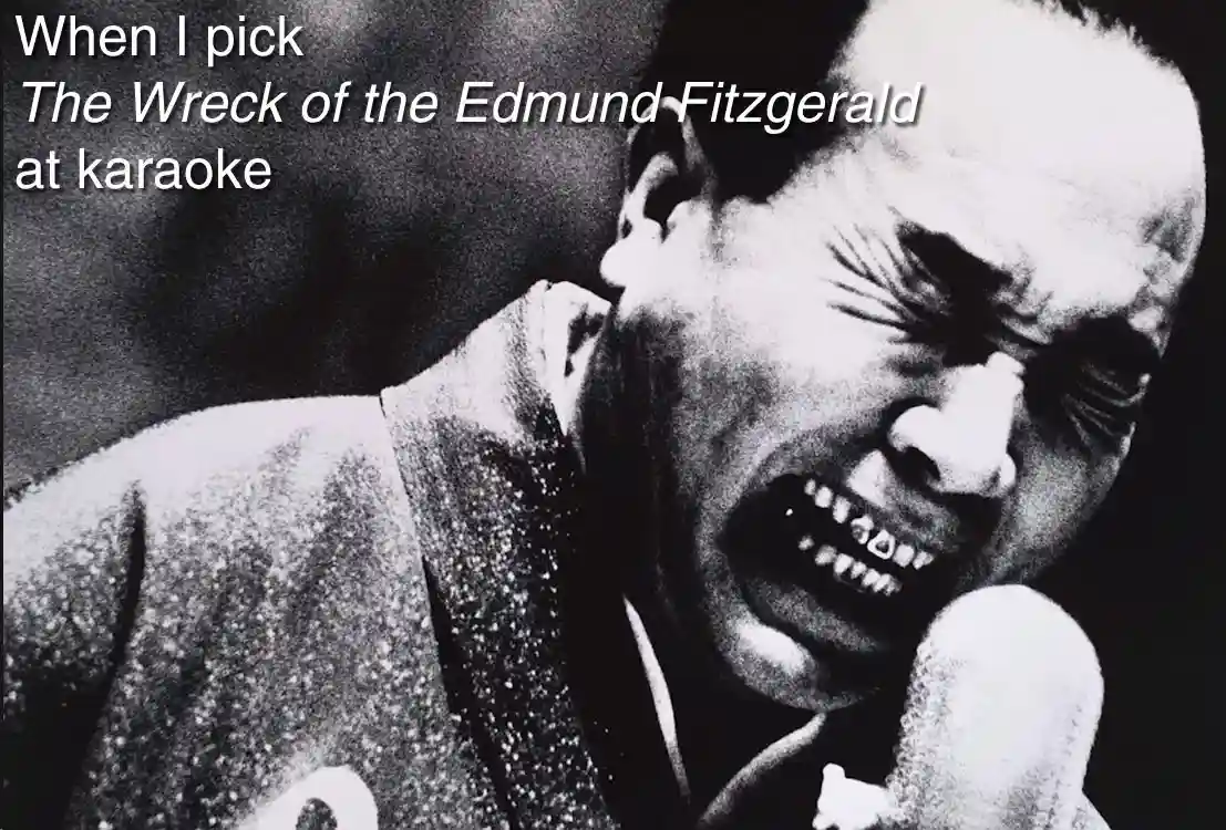 A black and white photo shows a man in a suit singing into a microphone with an intense, strained facial expression. The…