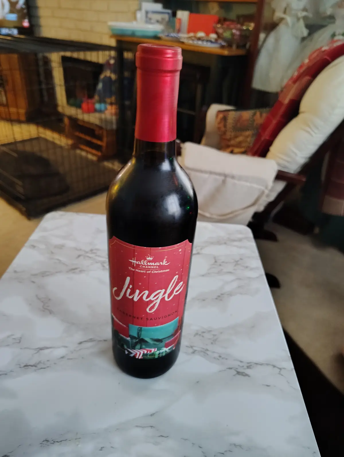 A bottle of red wine with a red label reading 'Hallmark Channel The Heart of Christmas Jingle Cabernet Sauvignon' sits on a…