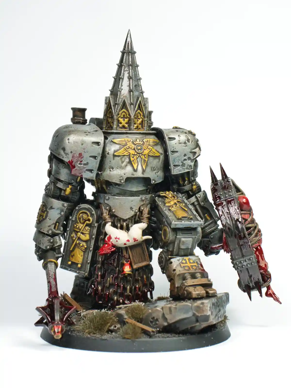 A heavily detailed, blood-splattered, silver-and-gold armored miniature of a Warhammer 40,000 character stands on a rocky…