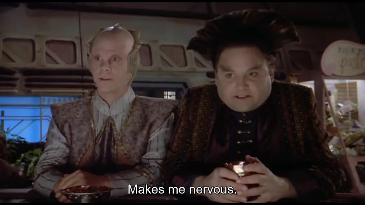 Two alien characters from Star Trek: Deep Space Nine sit at a table, looking visibly anxious. The character on the right…