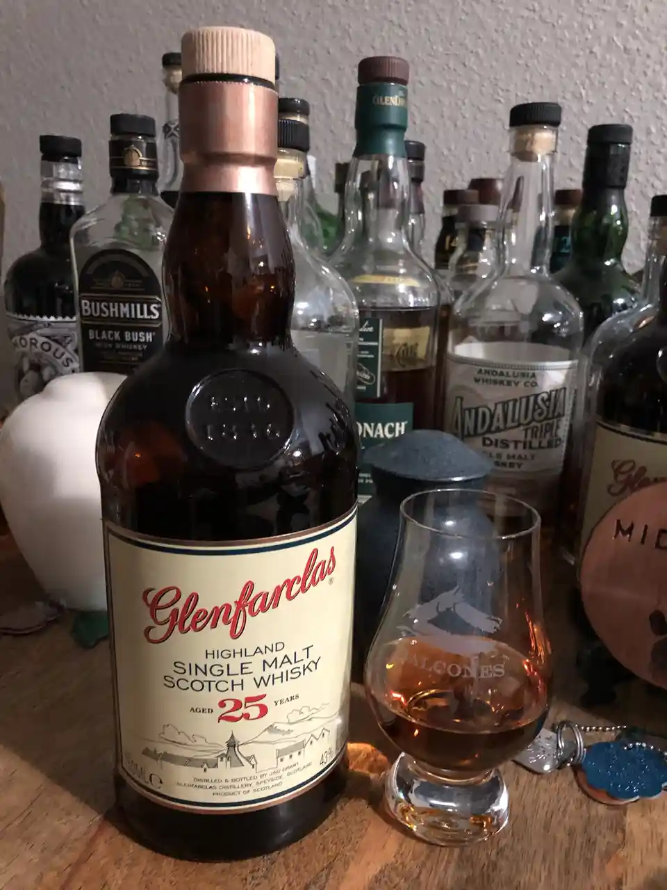 A bottle of Glenfarclas 25-year-old Highland Single Malt Scotch Whisky sits next to a tasting glass with a small amount of…