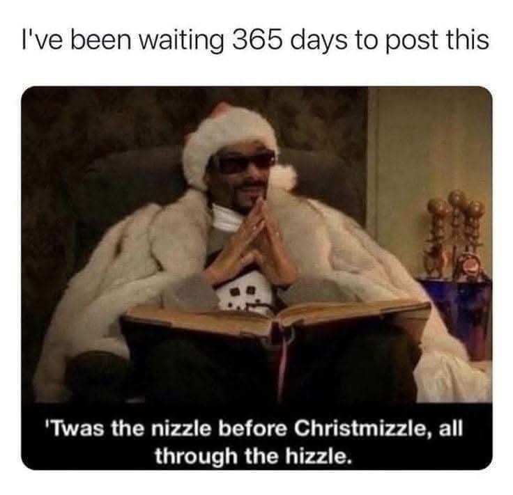 A man wearing a Santa hat and sunglasses sits in a chair, draped in a white fur coat, with his hands clasped in prayer while…