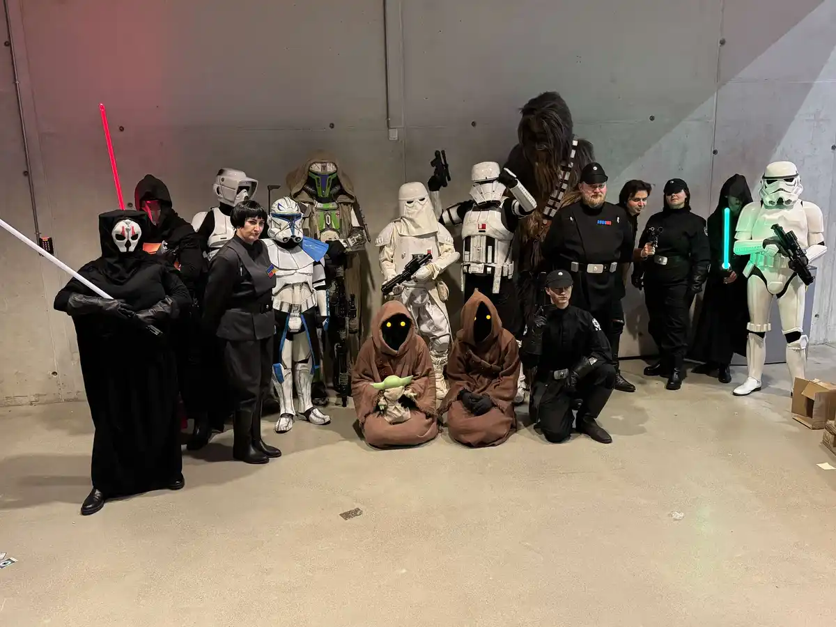 A group of people dressed as Star Wars characters, including Stormtroopers, Jedi, and Sith, pose for a photo. Two figures in…