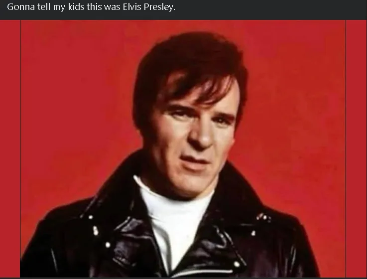 A man with dark hair and a serious expression wears a black leather jacket over a white turtleneck against a solid red…