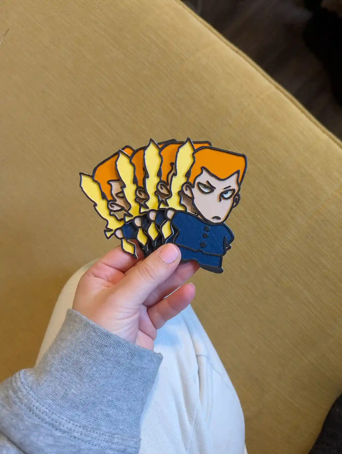 A hand holds a fanned-out stack of ten identical 3D-printed enamel pins, each depicting the anime character Ryo Hazuki from…
